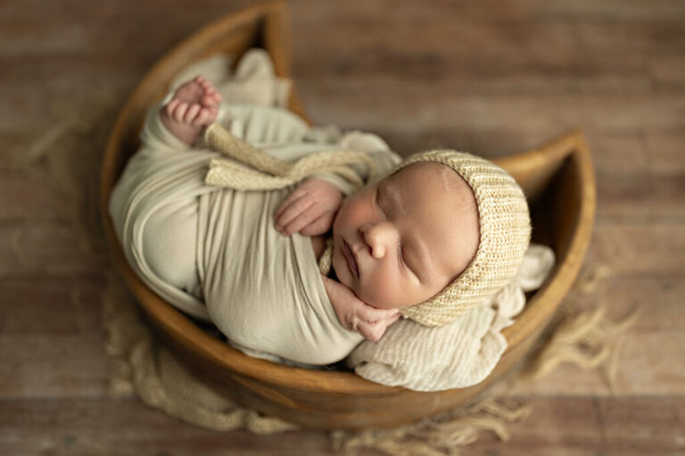 sleeping newborn baby posed in wooden moon bowl newborn photography session
