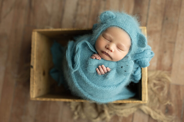 Salt Lake City newborn photography studio baby wrapped in blue knit set in wooden box